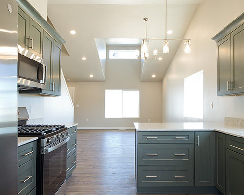 Smart Dwellings Gutenberg home with expanded kitchen, green shaker cabinets and vaulted living room with dormer window>