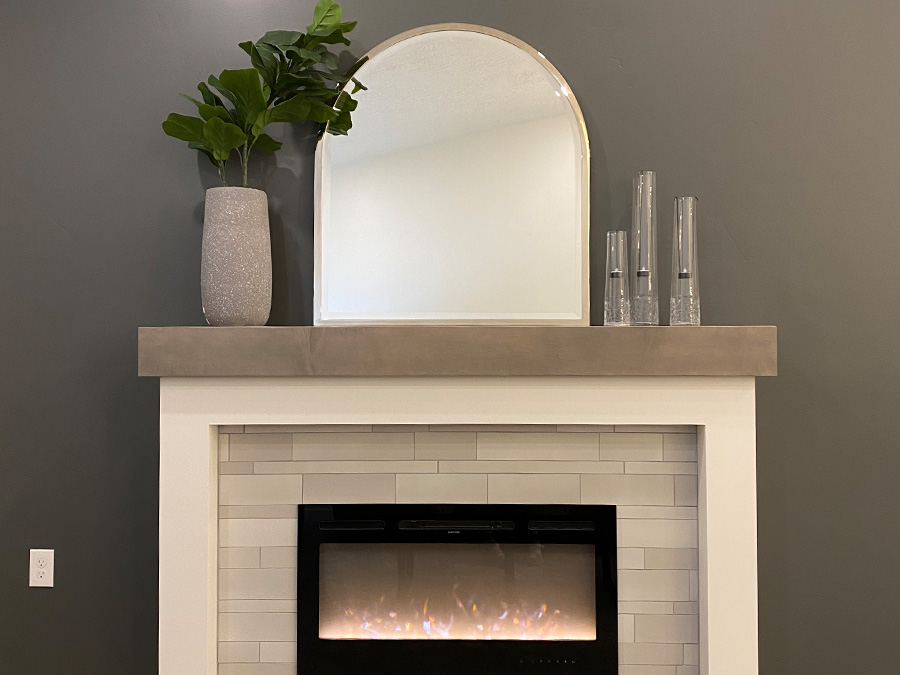 gas fireplace with mirror over mantle and plants