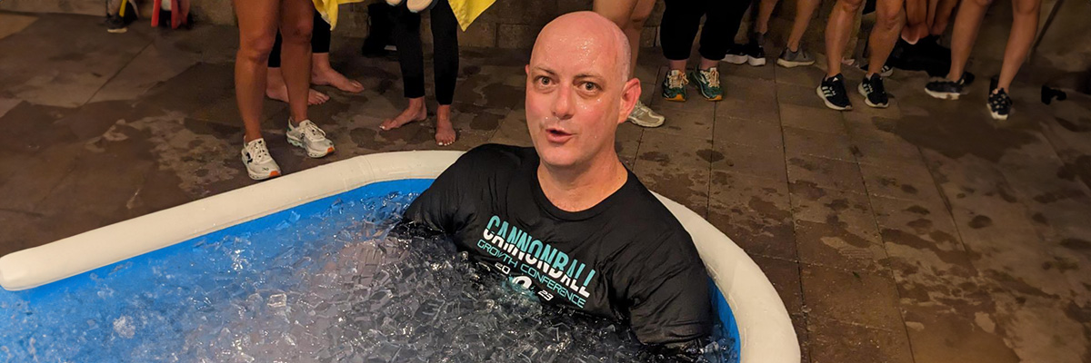 bald man trying hard to not panic as he sits in an ice bath after running a 5K at Cannonball Moments