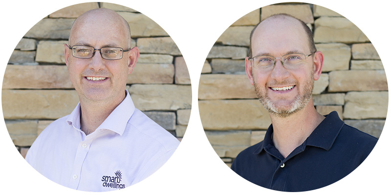 Photo of brothers Nathaniel and Justin in dress shirts standing outside by stone wall