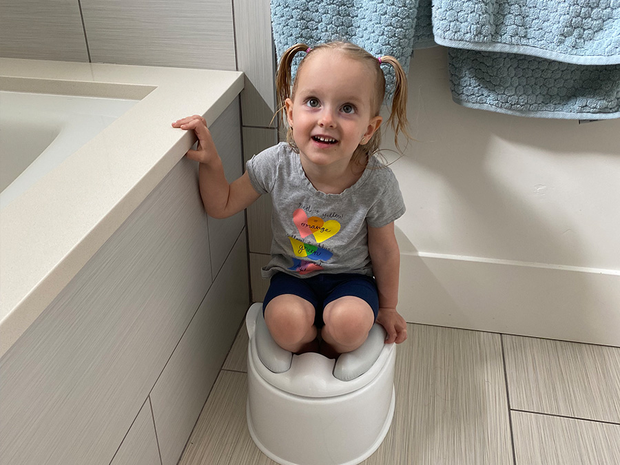 potty training little girl standing in her toilet fully clothed