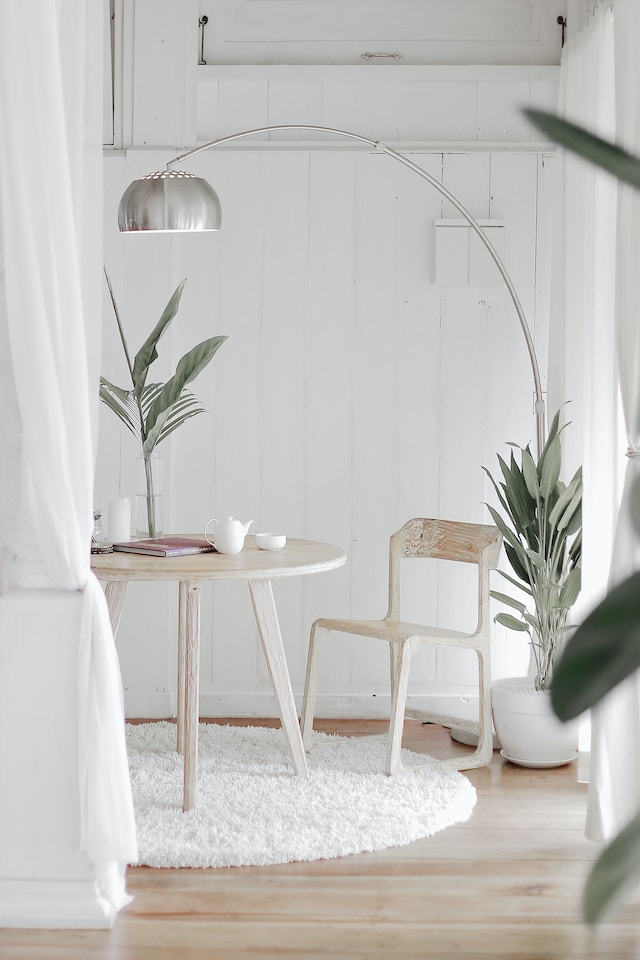 delicate white on white and off white small table with delicate chairs and stand lamp demonstrating proportion in design