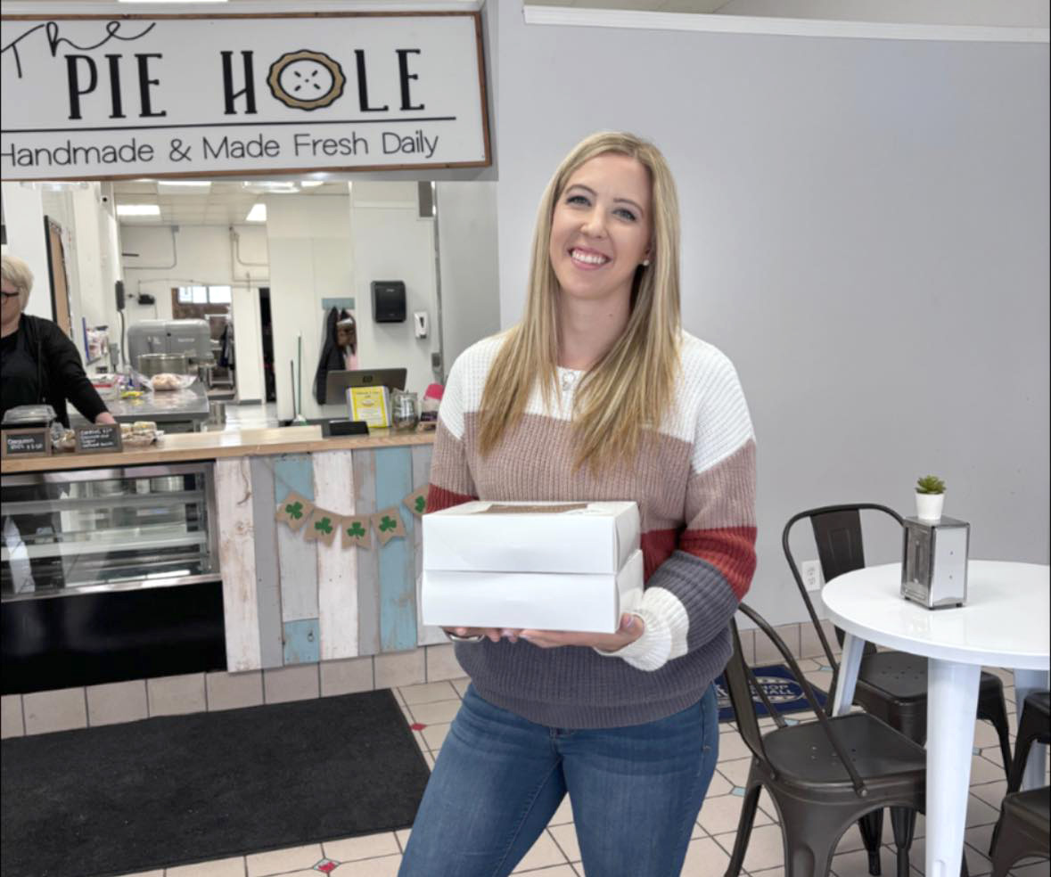 Smiling Blond woman holds two white pie boxes at local evanston shop: The Pie Hole