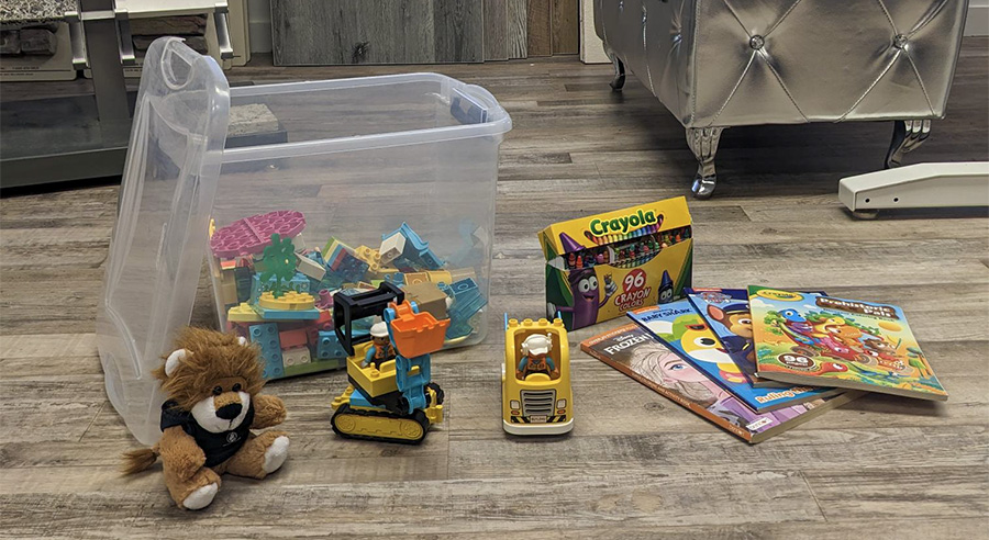 a variety of toys laid out in a pleasing way - stuffed animals, coloring books, LEGOS, and trucks