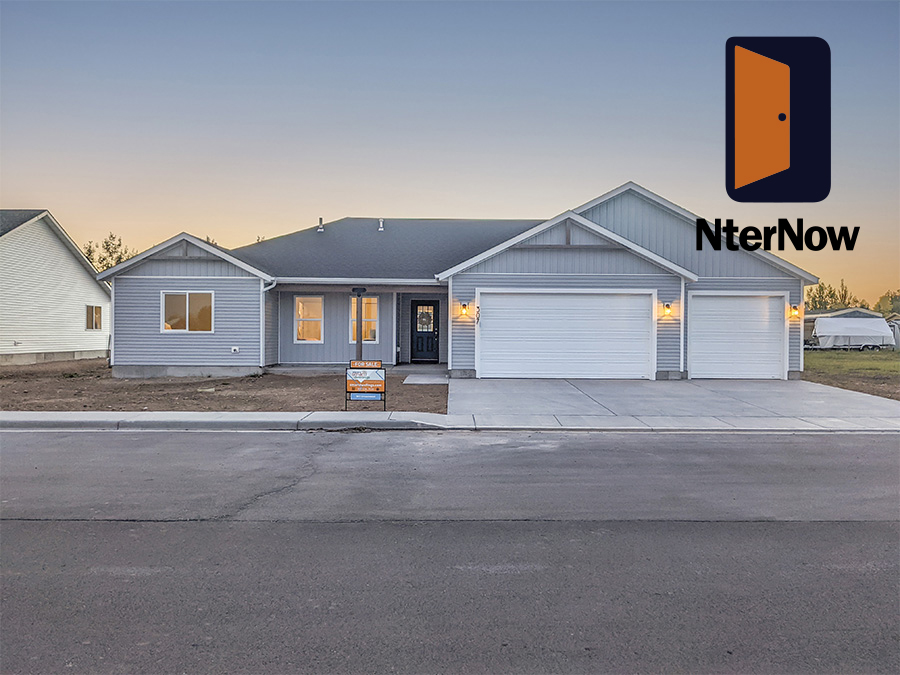 Evening Photo of Lovely Ranch home with grey blue siding, front porch with wreath on the door. Sunset in the background. Evening Photo of Lovely Ranch home with grey blue siding, front porch with wreath on the door. Sunset in the background.