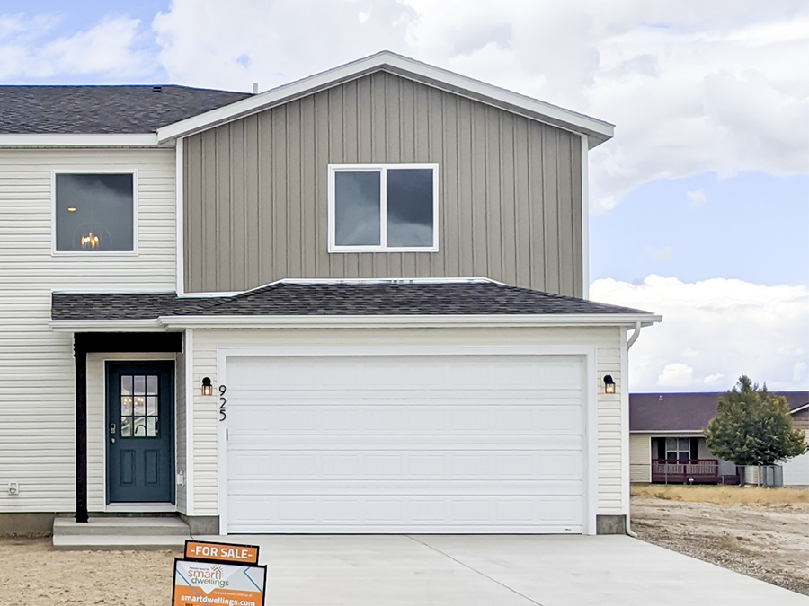 Front exterior view of new twin home with dark ocean blue front door, white 2-car garage, taupe accents, and vaulted entryway - a new build by Smart Dwellings